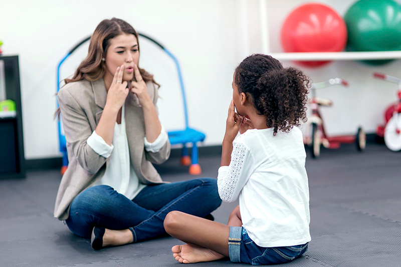 Stock Image of a woman and child participating in speech or audiology therapy.